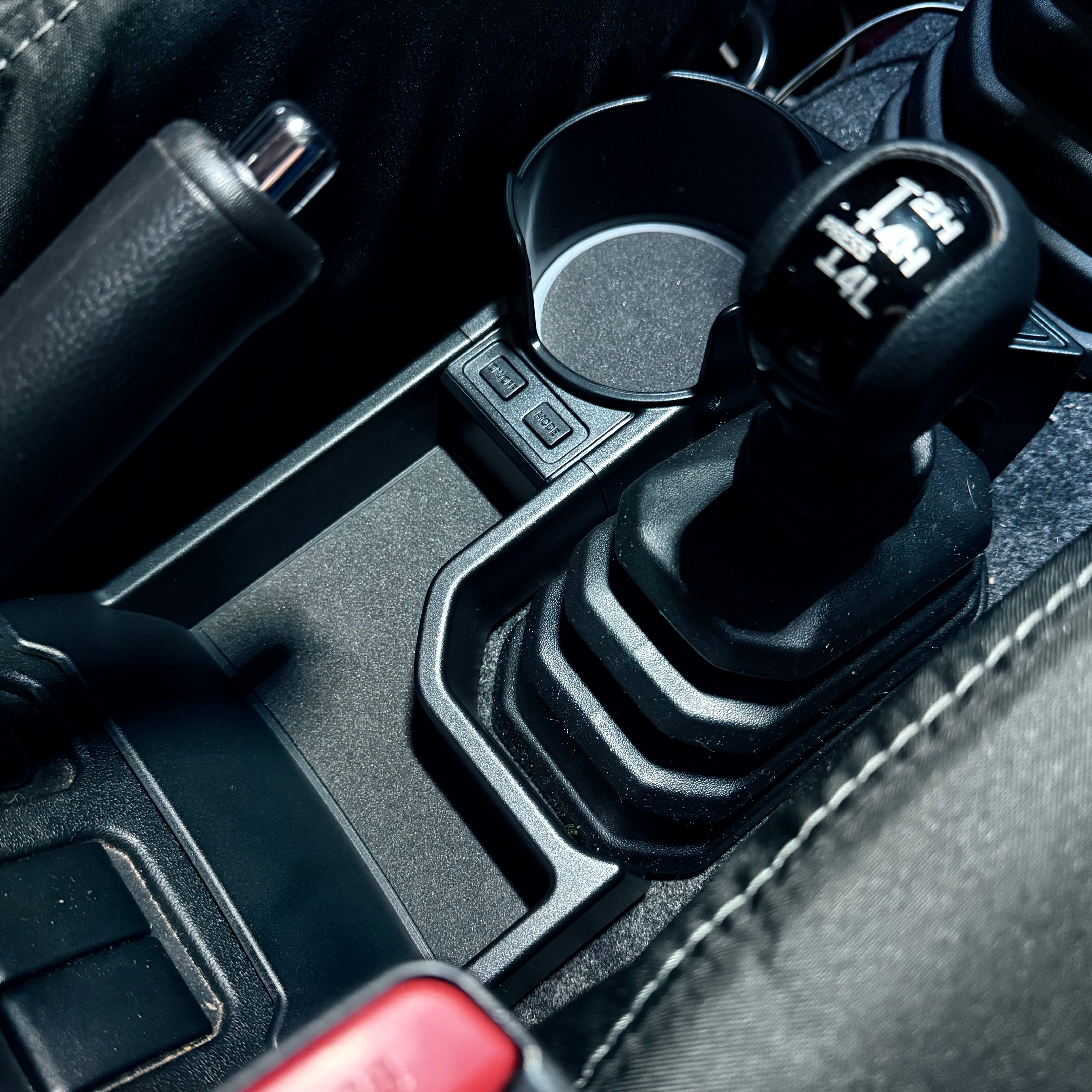 Close-up of a car gear shift lever with cup holder and USB port.